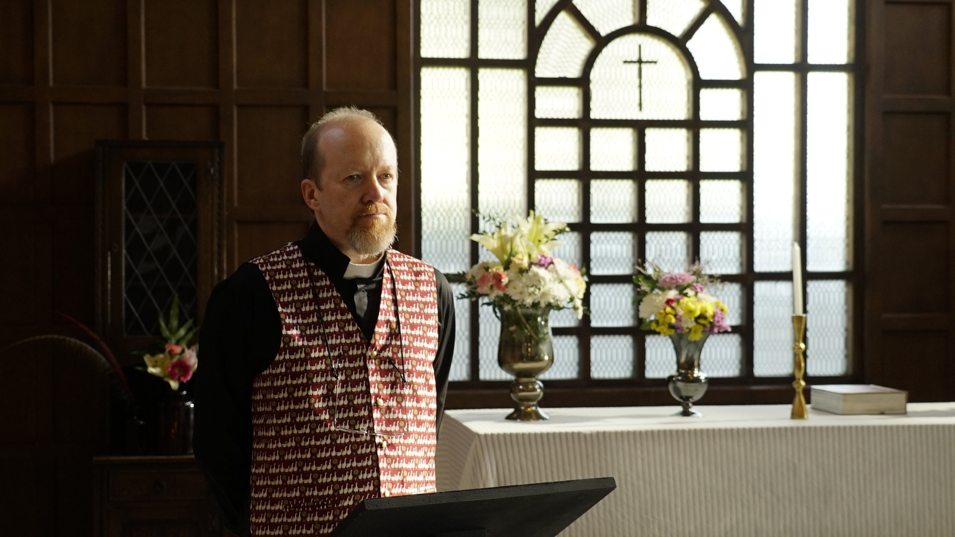 Father Daniel reading inside a church in a scene from Crushed.